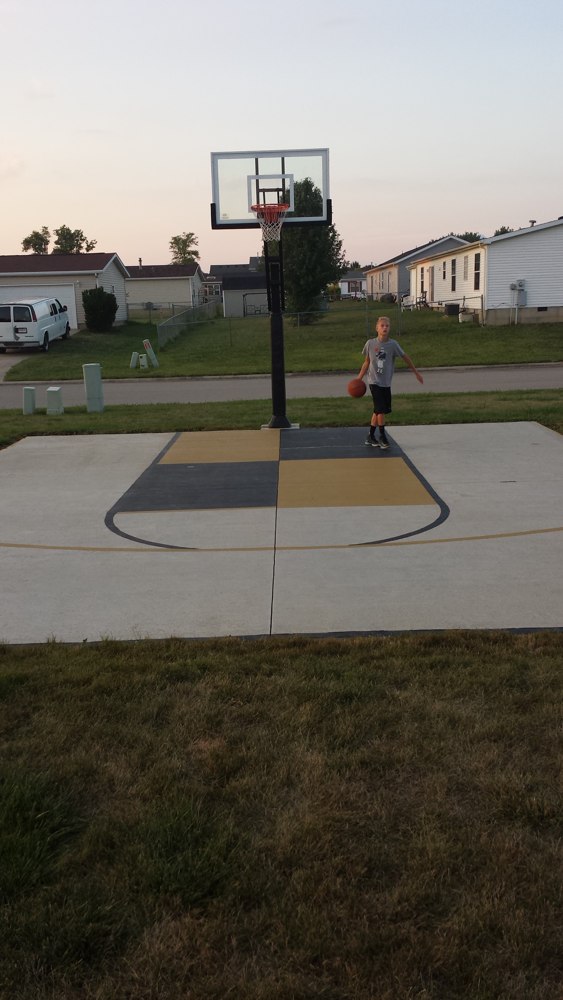 Players dribbles inside the the key. The Pro Dunk Gold basketball hoop sits center.